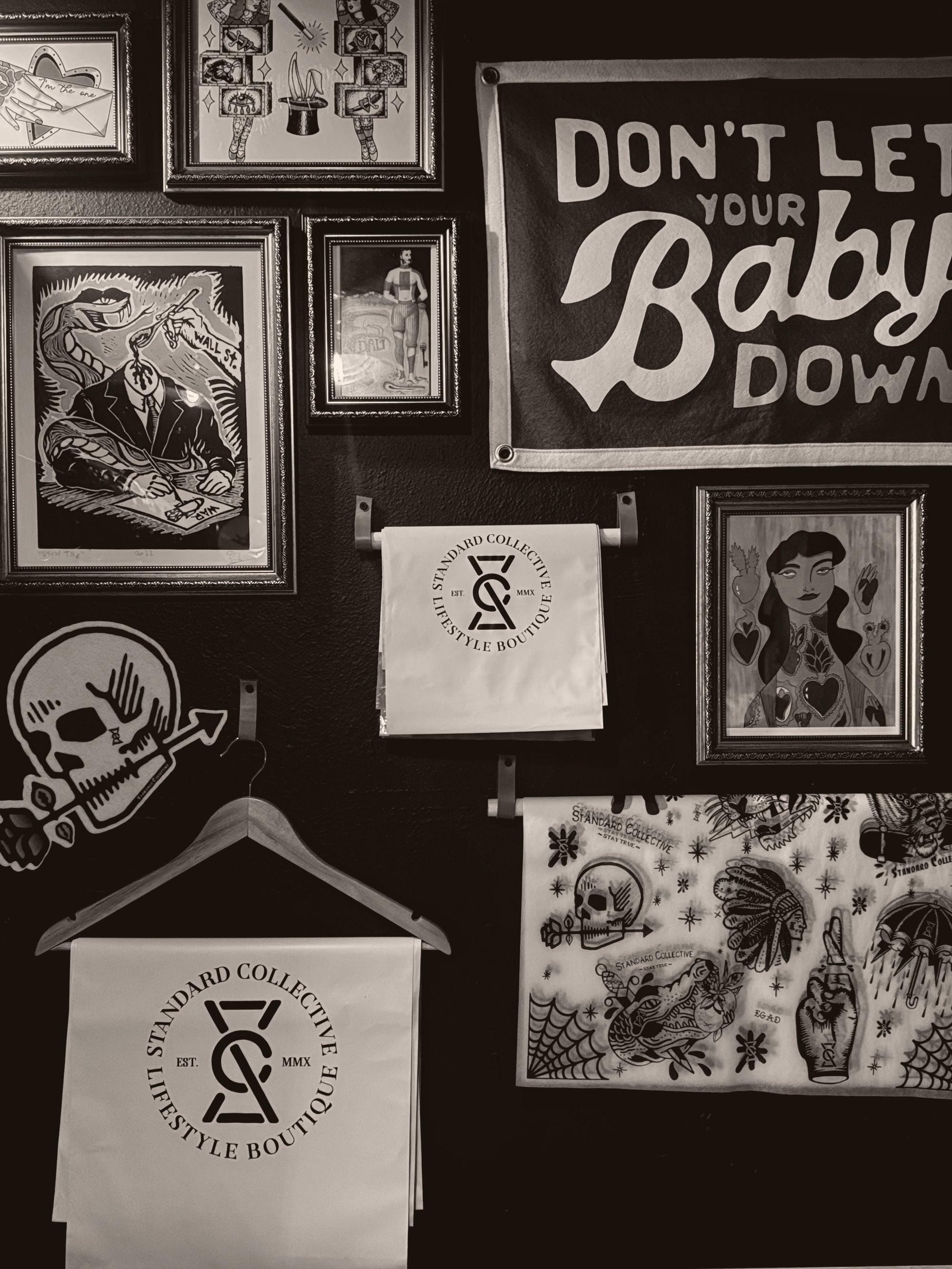 Wall with framed artwork, a sign, and a hanger with a bag featuring a logo.