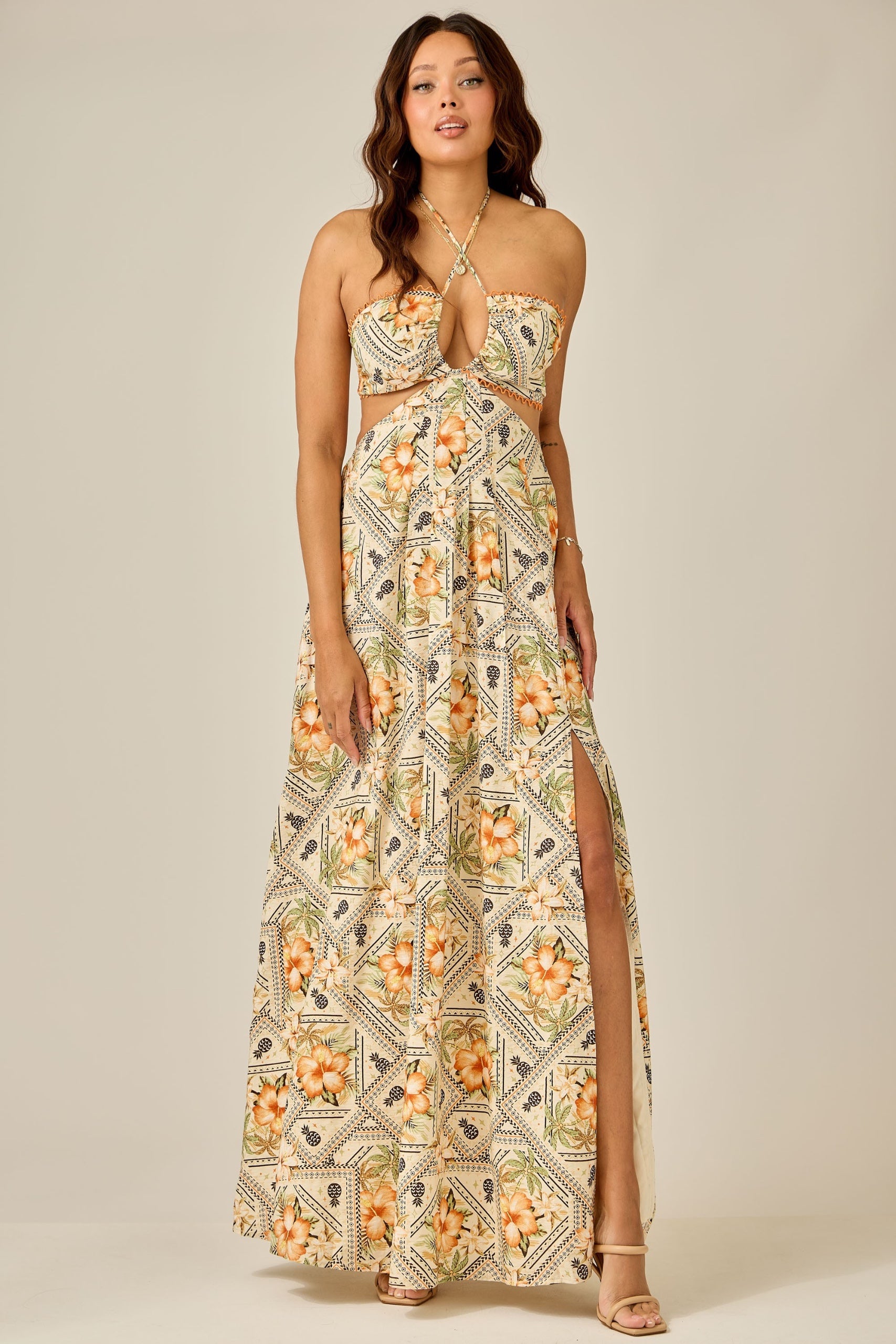 Woman wearing a floral patterned dress with a slit on a plain background