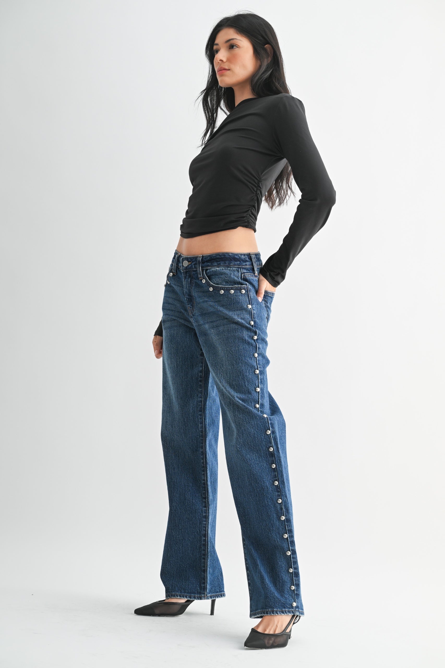 Woman wearing blue jeans with decorative buttons on a white background