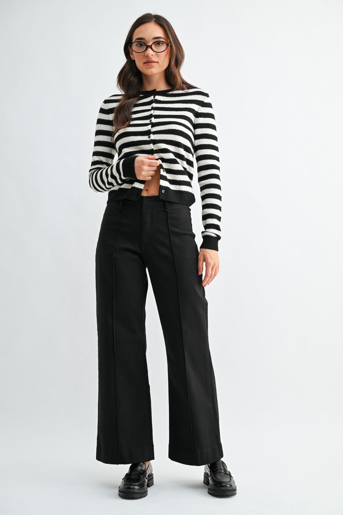 Woman wearing a black and white striped shirt and black pants on a white background