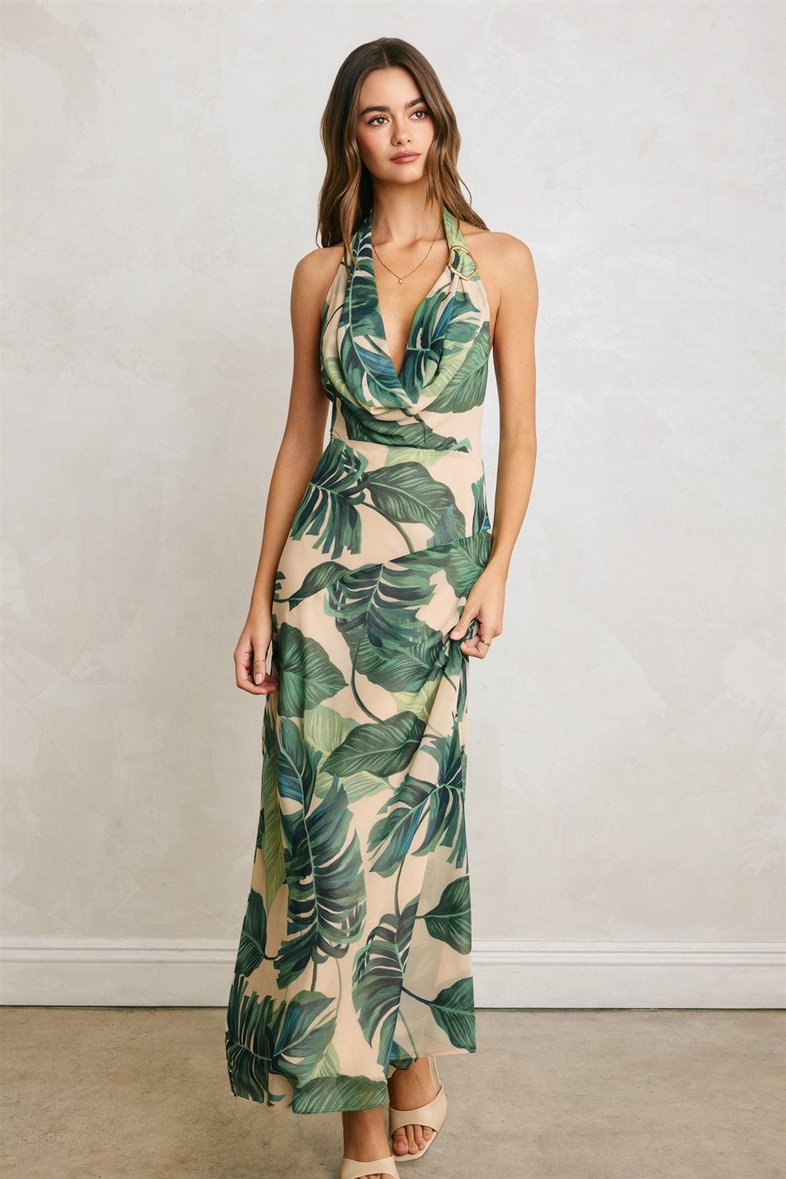 Woman wearing a tropical leaf patterned dress against a plain background