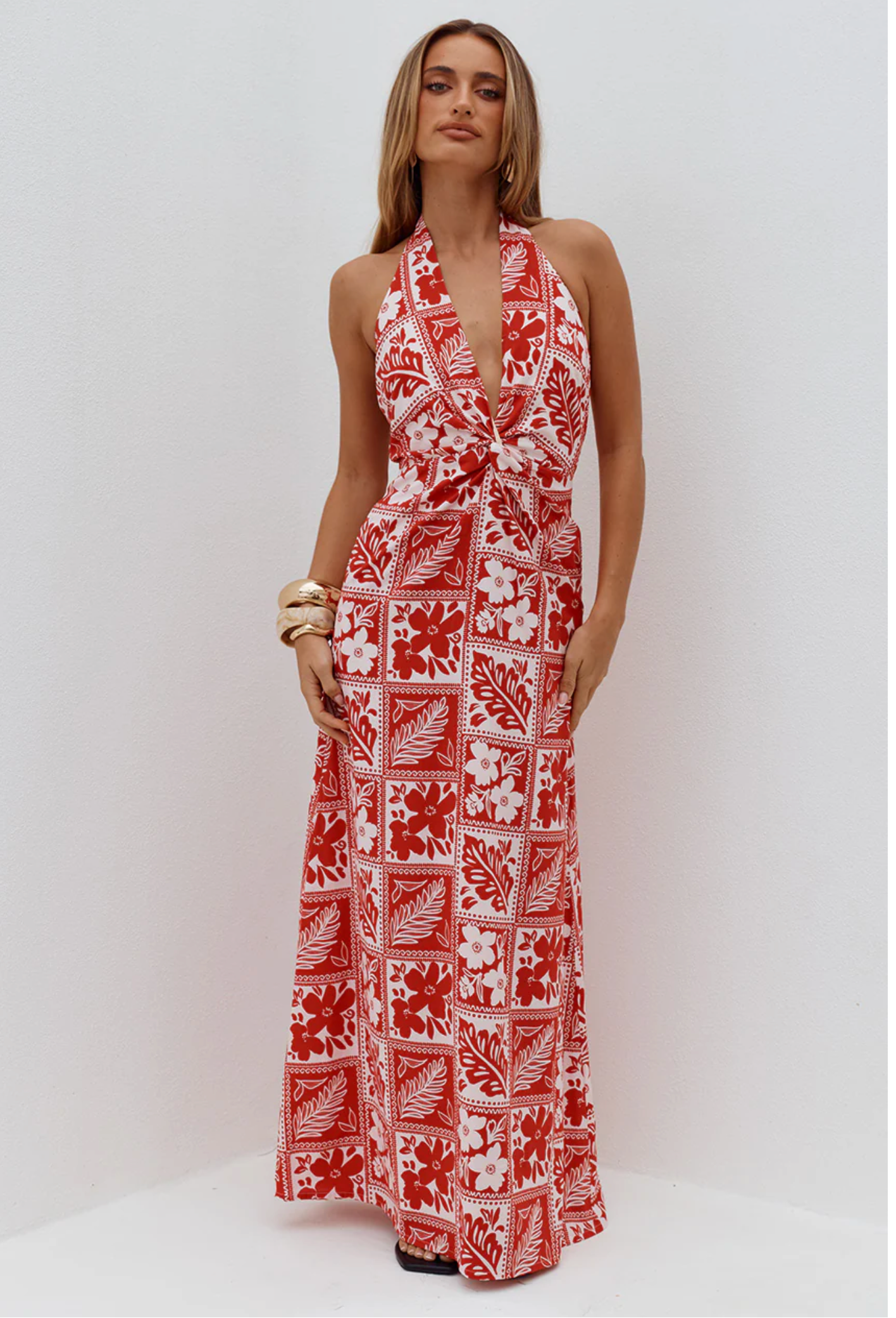 Woman wearing a red and white patterned halter neck dress on a white background