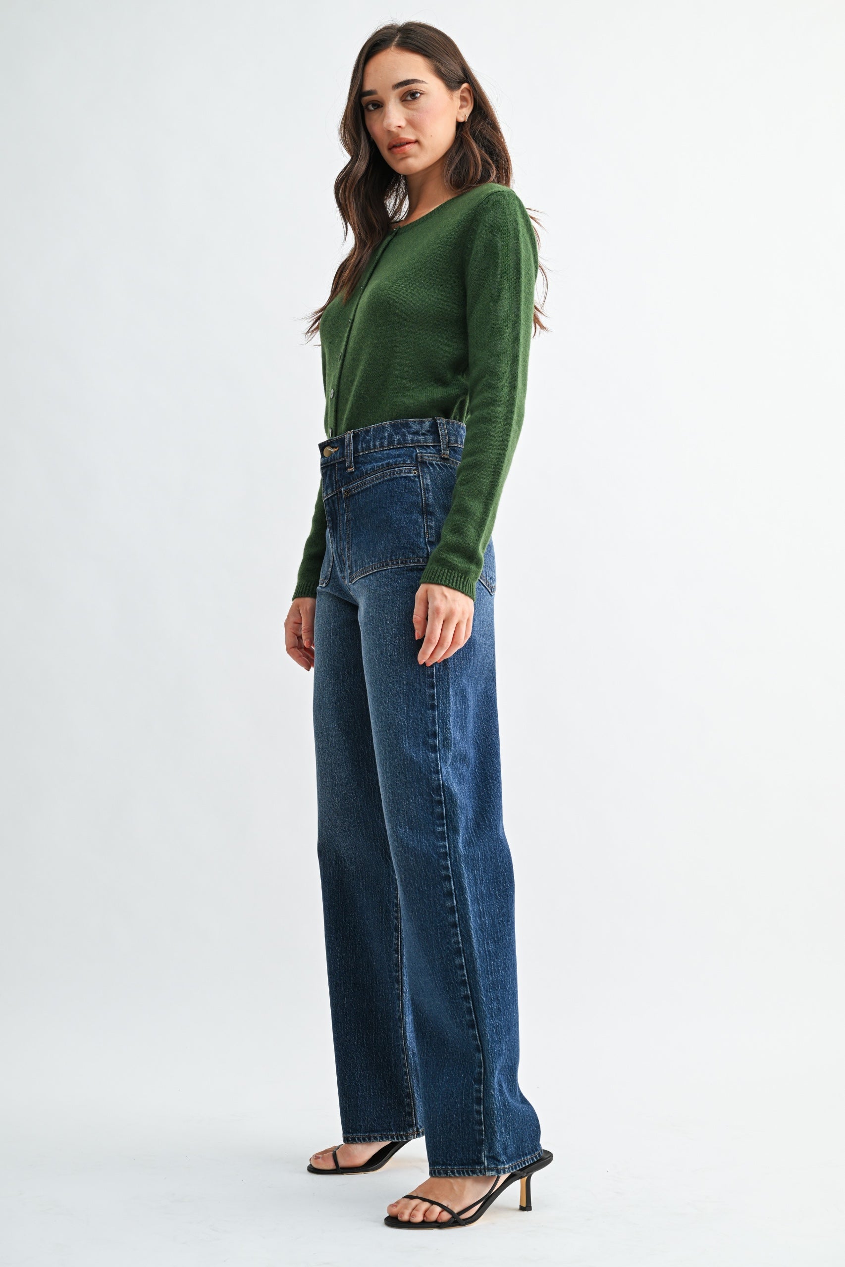 Woman wearing a green sweater and blue jeans on a white background